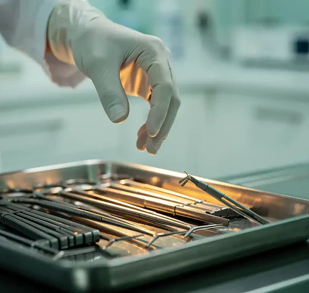 Gehandschoende hand van zorgverlener boven klinische instrumententray met bijna-gevallen instrument, steriele omgeving met amberkleurig accent.
