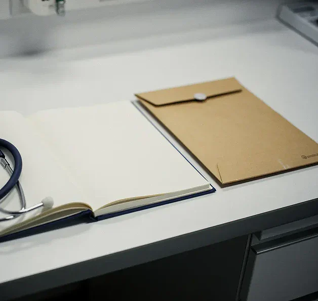 Open notitieboek van een medisch onderzoeker op een klinisch bureau naast een stethoscoop en verzegelde bewijsmap.